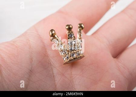 Die kleine Modellkrone wird in die Hand gelegt Stockfoto