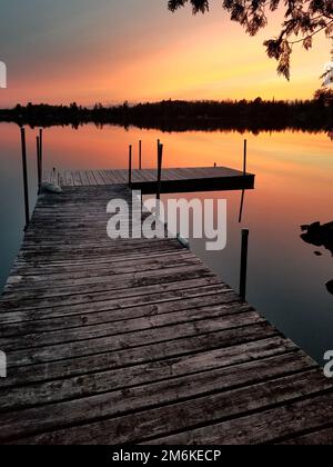 Sonnenuntergang auf einem ruhigen See in Minnesota mit Holzsteg im Vordergrund Stockfoto