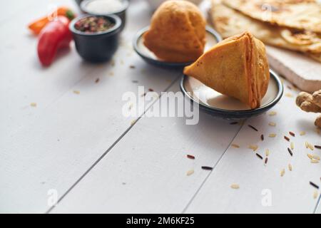 Traditionelle indische Snacks Samosa serviert auf einem Teller auf einem weißen Holztisch Stockfoto