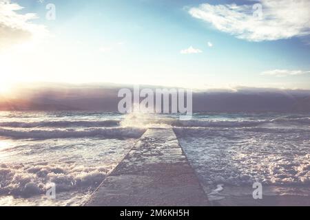 Große Wellen, die am Steinsteg bei stürmischem Wetter zerbrechen. Stockfoto