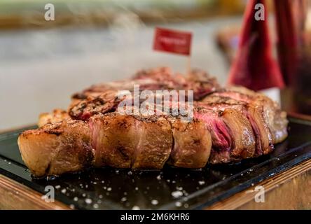 Klassisches gebratenes, trockenes, gereiftes T-Bone Florentiner Steak von einer Chianina-Kuh, die in einem Restaurant in Florenz, Italien, auf einer Servierplatte vom Grill dampft Stockfoto