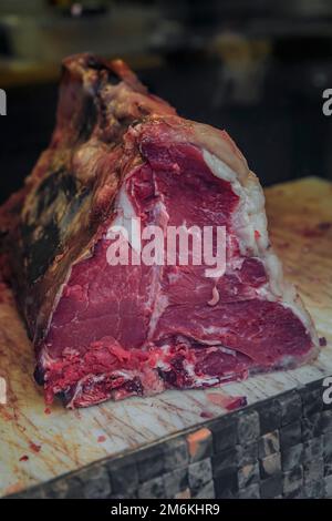 Klassisches ungeschnittenes Stück trockenes, gereiftes T-Bone Florentiner Steak von einer Chianina-Kuh auf einem Metzgertisch in einem Restaurant in Florenz, Italien Stockfoto