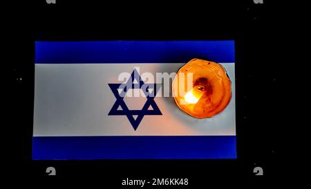 Israelische Flagge und brennende Kerzen darüber, Holocaust-Gedenktag Stockfoto