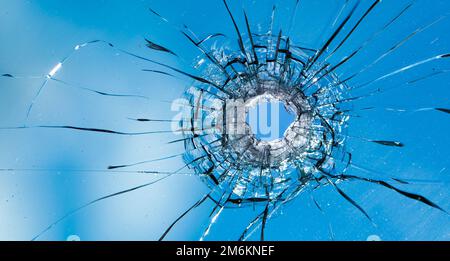 Einschusslöcher im Fenster gegen den blauen Himmel. Folgen von Schalen. Stockfoto