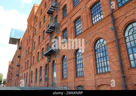 Fassade eines alten Ziegelgebäudes. Altes Fabrikgebäude mit Fenstern in der polnischen Stadt Lodz Stockfoto