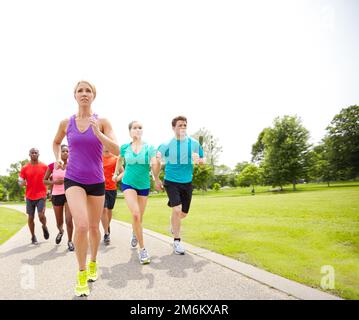 Förderung einer gesunden Gewohnheit. Vorderansicht einer Gruppe männlicher und weiblicher Athleten, die auf einer Outdoor-Rennstrecke laufen. Stockfoto