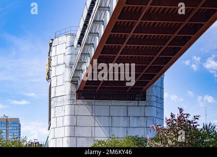 Technische Konstruktion der U-Bahn-Brücke mit Betonstützen, Ansicht von unten. Panorama der Stadt mit Himmel und Bäumen Stockfoto