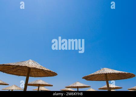 Bambusschirme am Strand mit klarem blauem Hintergrund am Sommertag Stockfoto