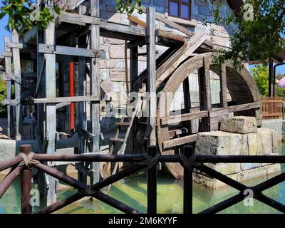 Russland, Sotschi 14.05.2022. Wassermühle mit Holzrad und Holzbalken in einem grünen Teich an einem Frühlingstag. Antike Technologie und Stockfoto