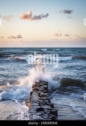 Bei Sonnenuntergang Plätschern Wellen Auf Groyne Am Shore Against Sky Stockfoto