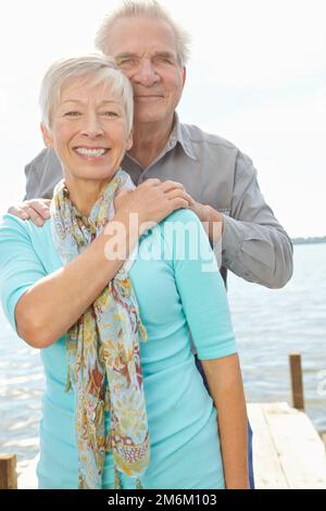 Glücklich pensioniert. Bild eines älteren Mannes, der hinter seiner Frau steht und ihre Hände auf ihre Schultern legt. Stockfoto