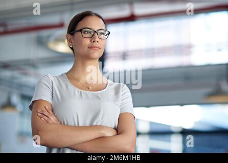 Die Zukunft ist bereit für Veränderungen. Selbstbewusste Geschäftsfrau, die mit einem Industriegebiet im Hintergrund umsichtig wegsieht. Stockfoto