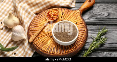 Schwarzes Pfefferpulver mit Knoblauch und Rosmarin auf dunklem Holzhintergrund Stockfoto