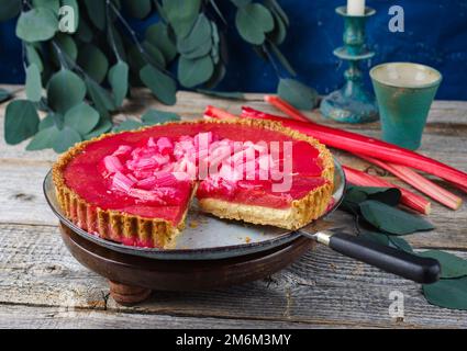 Moderner traditioneller deutscher Rhabarber-Ricotta-Kuchen mit Pudding und Gemüse, serviert aus nächster Nähe auf einer Platte im nordischen Design Stockfoto