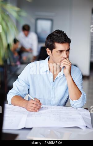 Er überlegt sich sein Design. Ein junger Architekt, der Designprobleme überwindet, während er an seinen Entwürfen arbeitet. Stockfoto