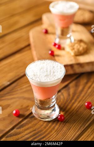 Ein Schuss köstlicher Pudding mit Kokosnussplatten und Preiselbeere auf einem Holztisch Stockfoto