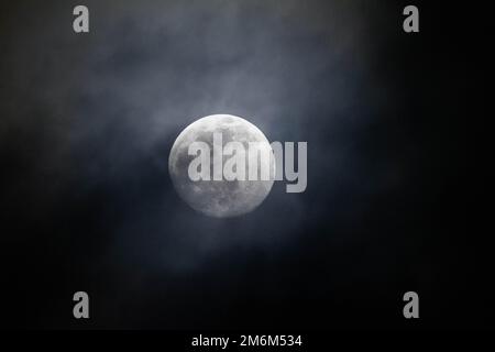 Ein Vollmond, der einen wolkigen Nachthimmel erhellt Stockfoto