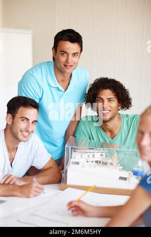 Das sind die besten Architekten der Gegend. Eine Gruppe von Architekten, die während einer Besprechung ein Gebäudemodell diskutieren. Stockfoto