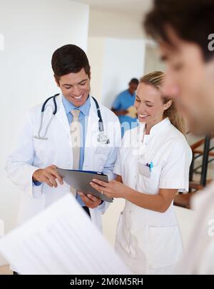 Besprechung von Behandlungsspezifikationen. Ein männlicher Arzt und eine Krankenschwester diskutieren über Krankenakten. Stockfoto