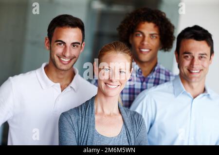 Sie haben eine exzellente Einstellung. Eine Gruppe von zwanglosen Geschäftsleuten, die zusammenstehen und lächeln. Stockfoto