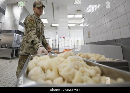 Airman 1. Class Alexander Ford, 374. Force Support Squadron Samurai Café Dining Facility Food Service Journeyman, bereitet Blumenkohlgemüse als Teil des Mittagessens am Yokota Air Base, Japan, 30. April 2022 zu. Das DFAC-Team des Yokota Samurai Café besteht aus US-amerikanischen Servicemitarbeitern und japanischen Mitarbeitern, die zusammenarbeiten, um durchschnittlich mehr als 500 Mahlzeiten pro Tag für die Basisbevölkerung zu servieren. Yokotas Restaurant wurde zum zweiten Mal in Folge 2022 mit dem Air Force John L. Hennessy Food Service Excellence Award für die Region 2 ausgezeichnet. Der DFAC von Yokota wurde aufgrund seiner herausragenden Leistungen im Bereich Mensch ausgewählt Stockfoto