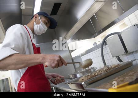 Tomohiro Ishisha, 374. Force Support Squadron Samurai Café Dining Facility erster Koch, bereitet Fleischbällchen als Teil des Mittagsmenüs am Yokota Air Base, Japan, am 30. April 2022 zu. Das DFAC-Team des Yokota Samurai Café besteht aus US-amerikanischen Servicemitarbeitern und japanischen Mitarbeitern, die zusammenarbeiten, um durchschnittlich mehr als 500 Mahlzeiten pro Tag für die Basisbevölkerung zu servieren. Yokotas Restaurant wurde zum zweiten Mal in Folge 2022 mit dem Air Force John L. Hennessy Food Service Excellence Award für die Region 2 ausgezeichnet. Das DFAC von Yokota wurde aufgrund seiner herausragenden Managementeffizienz ausgewählt Stockfoto