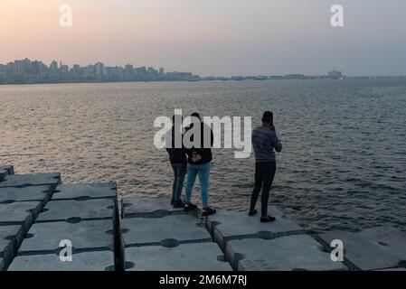 Alexandria, Ägypten. Dezember 1. 2022 Menschen auf Betonblöcken, die als Verteidigung gegen den steigenden Meeresspiegel entlang der Corniche von Alexandria, der, positioniert sind Stockfoto