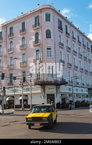 Alexandria, Ägypten. Dezember 4. 2022 Ein schwarz-gelbes Alexandria Taxi auf der Straße vor dem berühmten einst griechischen Café, dem Trianon und dem Paradise Inn, Stockfoto