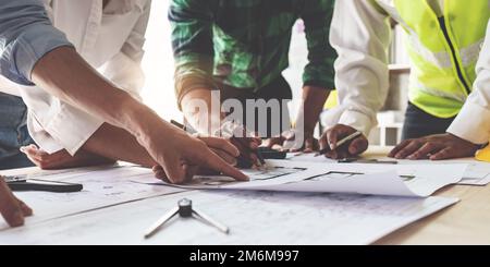 Architektenteam arbeitet mit Bauplänen für den Architekturplan, Ingenieur skizziert ein Bauprojekt, grünes Energiekonzept Stockfoto