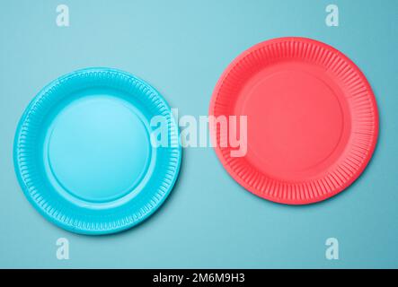 Leere blaue, rote Papiereinwegplatten auf blauem Hintergrund, Draufsicht Stockfoto