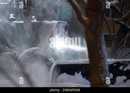 Schneeräumung im Winter. Vorderansicht eines Schneepflugs von städtischen Diensten, der schneebedeckte Straßen nach einem schweren Winterschneefall reinigt. Selektiver Fokus Stockfoto