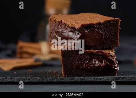 Gebackene Brownie-Schokoladenstückchen auf schwarzem Tisch, köstliches Dessert Stockfoto