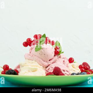 Vanille- und Himbeer-Eisschaufeln auf einem runden grünen Teller Stockfoto