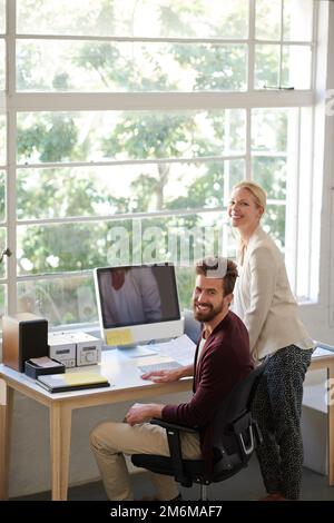 Finden Sie den richtigen Platz für ein positives Team. Männliche und weibliche Kollegen in einem entspannten Büro, die vor der Kamera lächeln. Stockfoto