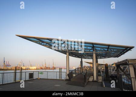 Der berühmte Anblick von Hamburg, der Landungsbrücken, an der elbe mit kleinen Booten. Leute, die durch einen Gang zum Pier laufen. Stockfoto