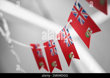 Eine Girlande mit Bermuda-Nationalflaggen auf abstraktem, verschwommenem Hintergrund. Stockfoto