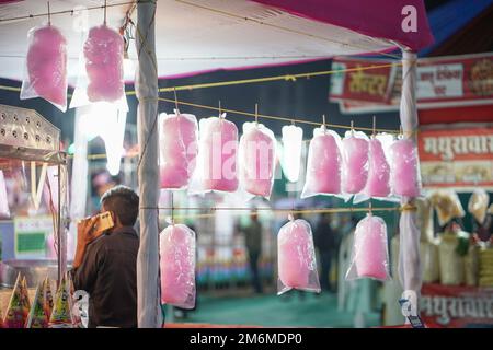 Leckere Zuckerwatte, die man auf dem indischen Vergnügungspark zum Verkauf aufhängen kann, leckere rosa Zuckerwatte, die auf dem indischen Markt des Vergnügungsparks verkauft wird Stockfoto