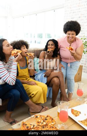Millennial Biracial Freunde genießen Pizza und Getränke, während sie Freizeit zusammen zu Hause verbringen Stockfoto