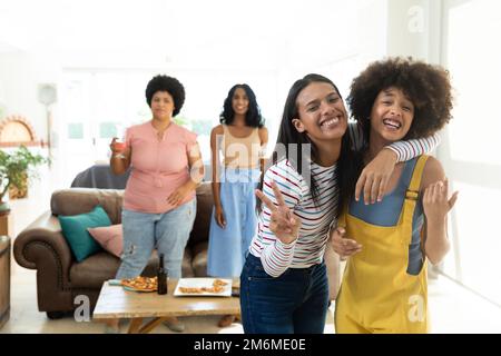 Glückliche Biracial junge Frau zeigt Frieden Zeichen, während mit Freunden zu Hause genießen, kopieren Raum Stockfoto