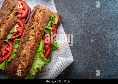 Zwei dunkle Ciabatta-Sandwiches mit grünem Salat, reifen roten Tomaten, Zwiebeln und Thunfisch Stockfoto