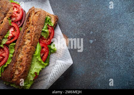 Zwei dunkle Ciabatta-Sandwiches mit grünem Salat, reifen roten Tomaten, Zwiebeln und Thunfisch Stockfoto