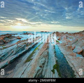 Twilight Ozean Küste mit geripptem stratiform Rock. Stockfoto