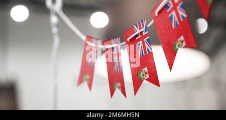 Eine Girlande mit Bermuda-Nationalflaggen auf abstraktem, verschwommenem Hintergrund. Stockfoto