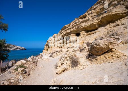 Der berühmte Matala Beach mit seinen Höhlen ist in den 70er Jahren für Hippies bekannt. Blick auf Felshöhlen, einst ein römischer Friedhof, am berühmten griechischen Strand Matala, Kreta, Griechenland. Stockfoto