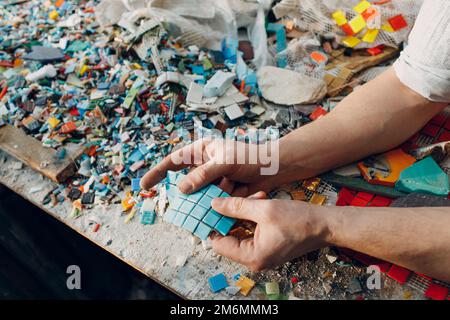 Mann Mosaiken Meister wählt ausgewählte Smaltglasstücke für Mosaik-Panel. Männlicher Mosaikist bei der Arbeit. Stockfoto