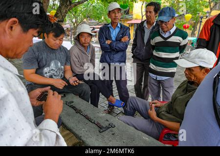 Hoi an, Vietnam - 29. Dezember 2022: Eine Gruppe von Männern, die Dominosteine auf einer Straße in Hoi an, Vietnam, spielen. Stockfoto