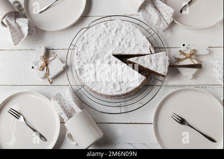 Couchtisch für ostern mit köstlicher Schokolade, Mandelkuchen, Tellern, Tassen und osterhasen auf weißem Tischhintergrund. Flach verlegt Stockfoto