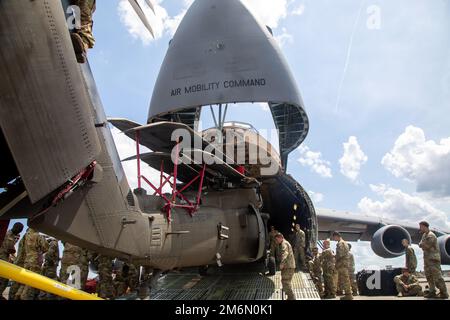 USA Soldaten der 3. Kampfluftfahrtbrigade, der 3. Infanterie-Division und Soldaten der 9. Luftaufstandsstaffel, 436. Luftwaffenflügel laden einen UH-60 Black Hawk Helikopter auf eine C-5M Super Galaxy, während sie ein gemeinsames Luftladungstraining am Hunter Army Airfield, Georgia, am 2. Mai 2022 durchführen. Diese Schulung ist von entscheidender Bedeutung, um sicherzustellen, dass die gemeinsamen Kräfte bereit sind, Ausrüstung sicher und effizient in Flugzeuge des Air Mobility Command zu laden, um eine schnelle globale Mobilität zu gewährleisten und die Energieprojektion zu bekämpfen. Stockfoto