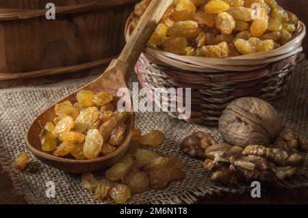 Rosinen in einem Korb und andere Früchte auf dunklem Holzhintergrund Stockfoto