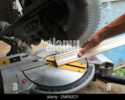 Markieren und Schneiden von Holzbohlen auf einer Gehrungssäge, einer Winkelsäge in einer Zimmermannswerkstatt bei der Arbeit mit Holzplatten Stockfoto